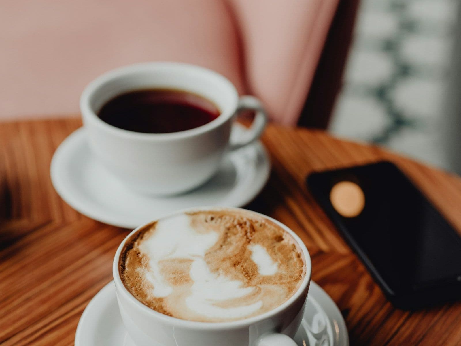 Two coffees and a phone on a cafe table