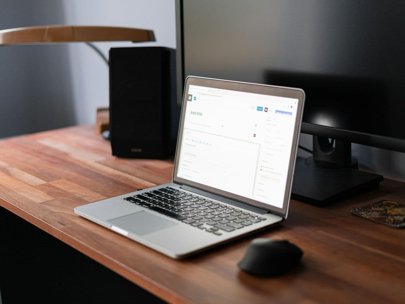 A laptop on a wooden desk with a page editor open
