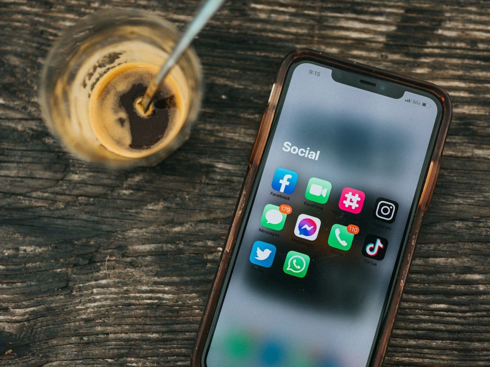 A phone showing social media apps beside a coffee